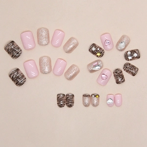 Press-on nails featuring pink hearts, silver glitter, and brown zebra pattern with rhinestones