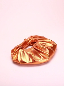 Detailed macro view of the glossy orange metallic leather and pleated texture of the pouch