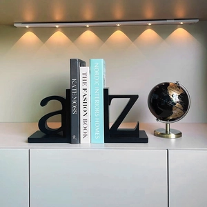 Modern black A-Z alphabet metal bookends supporting books on a white minimalist shelf