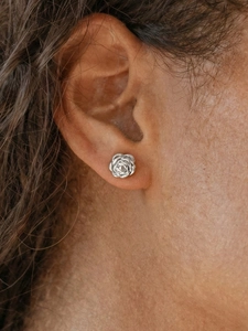 Detailed close-up of a silver 3D rose flower earring on a model ear with a polished finish