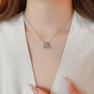 Close-up of sparkling silver pumpkin carriage pendant necklace with pink heart gemstone
