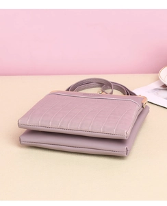 Detail of purple crocodile pattern shoulder bag with golden metal clasp and logo
