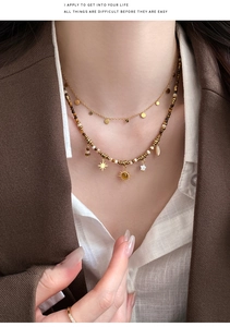 Detail of layered gold sun and star charms with tiger eye beads on ethnic style necklace