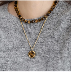 Detail of layered brown tiger eye bead necklace with a gold twisted chain and round pendant