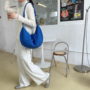 Detail of Klein blue pleated crescent bag showing durable nylon fabric and shoulder strap