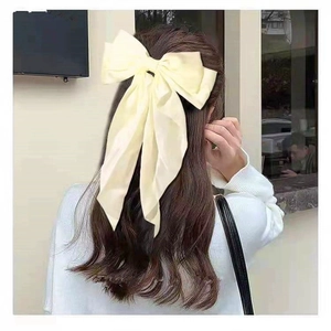Elegant cream white satin bow hair clip with long ribbons shown on a model's hair