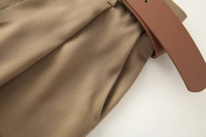 Gros plan du pantalon en satin kaki avec ceinture marron et détails de plis délicats