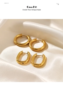 Close-up of chunky gold hoop and oval earrings on elegant white silk fabric background