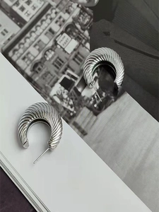 Detail shot of silver metal hoop earrings with spiral texture on a magazine background