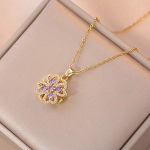 Golden necklace with spinning clover pendant featuring a purple zircon and white crystals