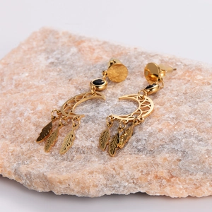 Golden crescent moon earrings with leaf pendants and black inlay on a natural stone base