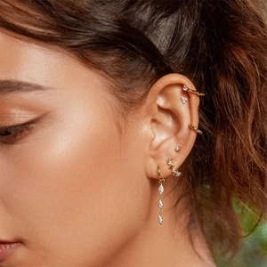 Close-up of gold plated geometric earrings set with sparkling zircon on model ear