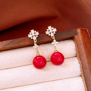 Detail view of 18K gold plated earrings with red beads and zircon flower studs in a box