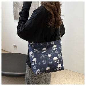 Close-up of a blue canvas tote bag with skull and vintage floral print with metal hooks
