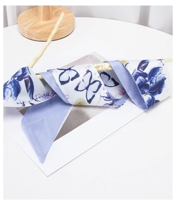 Detail of a purple butterfly and orchid printed long silk scarf on a wooden stand