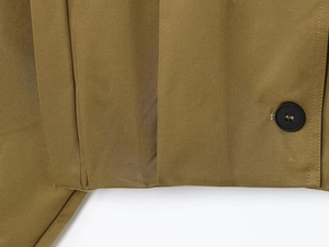 Close-up of olive green twill fabric detail with black button and precise stitching