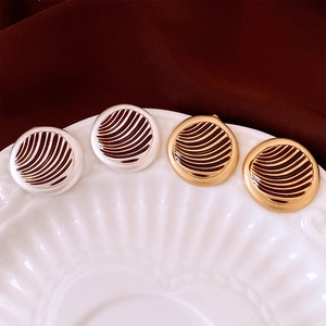 Detail of round textured earrings in gold and silver finish on a ceramic tray