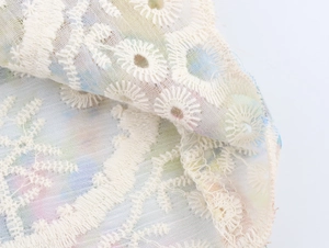 Détail macro de broderie florale délicate sur tissu en maille avec bord festonné