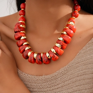 Close-up of red textured acrylic beads and golden metal spacers on a vintage sweater necklace