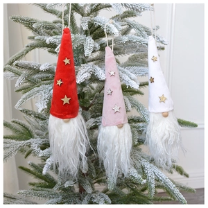 Three plush Christmas gnome ornaments in red, pink and white hanging on a frosted tree
