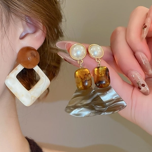 Detail of vintage geometric earrings with resin beads and marble textured fan pendants