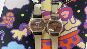 Dual-timezone Oulm watch detail showing stainless steel case back and leather straps