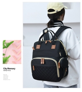 Detailed view of black quilted diaper backpack with leather handles and gold zippers