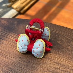 Detail of red and blue polka dot bow hair claw clip showing fabric texture and spring mechanism