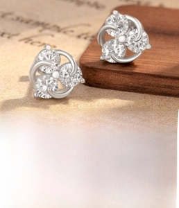 Close-up of silver steel ear studs featuring three cluster-set zircons with measurements