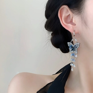 Elegante silberne Quastenohrringe mit blauen Schmetterlingskristallen an einem Modell