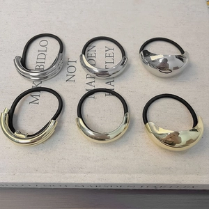 Detail of minimalist gold and silver metal hair ties set on a textured book surface