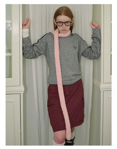 Detail shot of chunky knit pink scarf styled with a grey sweatshirt and burgundy skirt