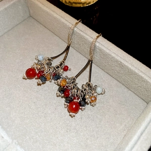 Détail macro de boucles d'oreilles pompons colorés avec zircons dans un écrin en velours
