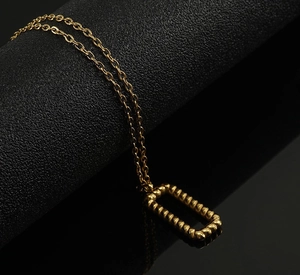 Detailed macro view of 18K gold rectangle pendant with twisted braided texture
