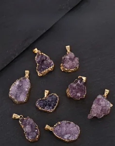 Detailed view of raw irregular amethyst pendants with elegant gold plated edges on black stone