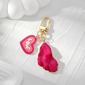 Detail of rose red heart charm and irregular resin crystal pendant with gold edges