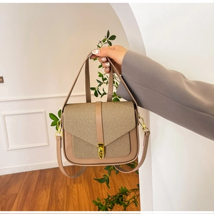 Close-up of brown leather saddle bag with woven khaki flap and gold buckle detail