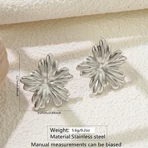 Detailed view of silver flower-shaped stainless steel stud earrings on textured surface