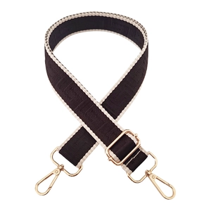 Close-up of geometric pattern jacquard bag strap with gold metal lobster clasps