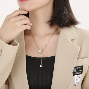 Macro view of gold cat eye stone pendant necklace on a model wearing a beige blazer