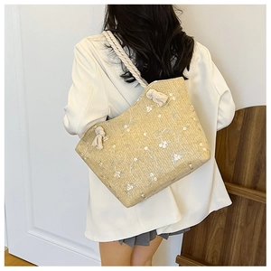 Détails du sac cabas en paille beige avec broderies de fleurs blanches et anses cordes