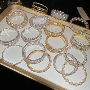 Elegant double-layer pearl bracelets with diamond accents on a gold-rimmed display tray
