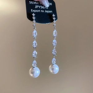 Detail of silver drop earrings with long tassels, zircon stones and white pearls