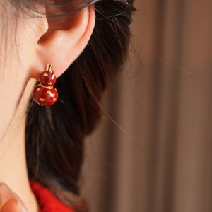 Close-up of a model wearing 18k gold plated red gourd earrings with a vintage design
