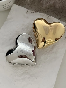 Detailed view of heart-shaped gold and silver metal hair claws on a textured surface