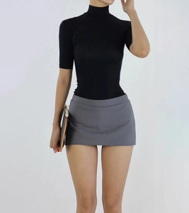 Detail of slim fit black high neck top paired with a grey mini skirt and brown clutch