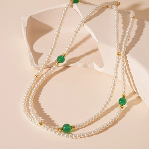 Détail du long collier vintage avec perles blanches, perles d'agate verte et dorures