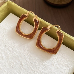 Detail of 18k gold plated square resin hollow earrings with retro marble pattern texture