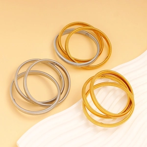 Detail of stacked spiral spring bangles in gold and silver finish on artistic tray