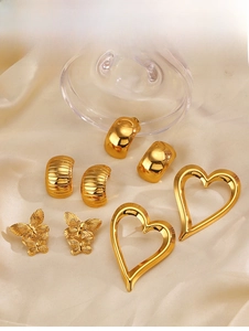 Detailed display of gold C-shaped earrings and heart studs on warm satin fabric